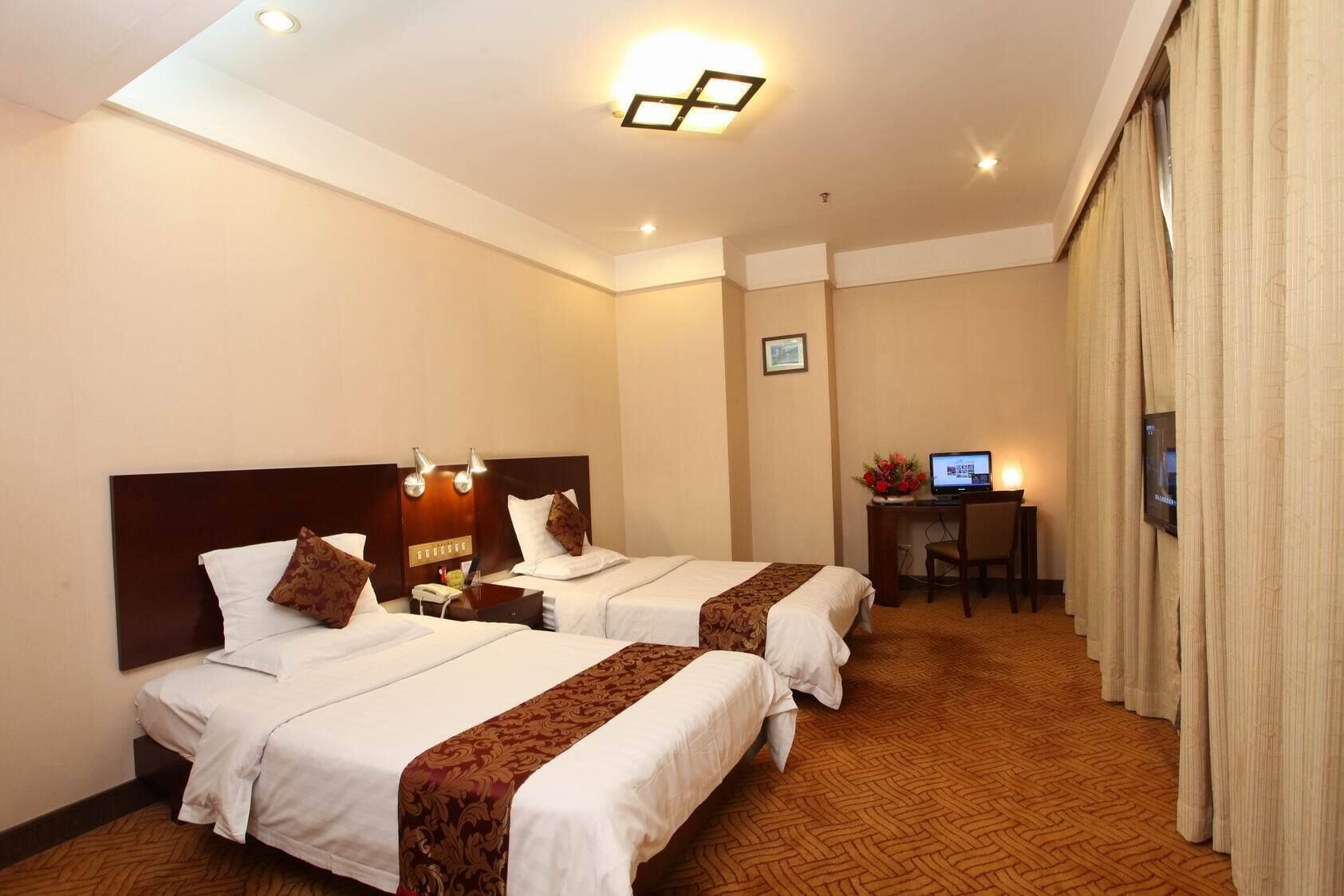 A hotel room with two beds, a desk with a computer, and a television.