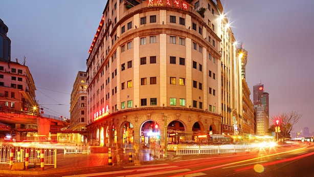Un hotel de varios pisos con fachada curva, grandes ventanales y una entrada destacada con arcos.