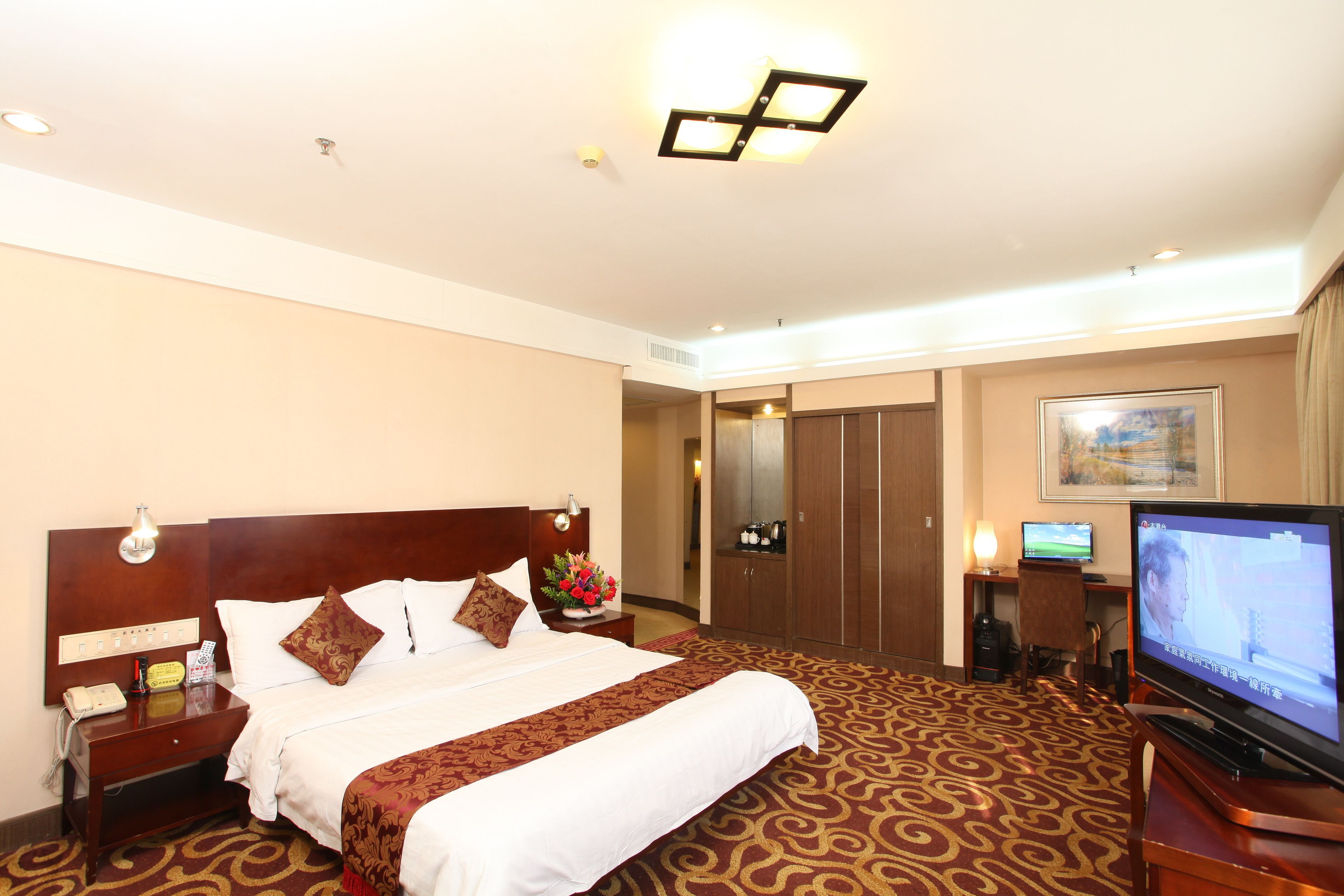 Una habitación de hotel con una cama grande, televisor, escritorio con computadora y armario.