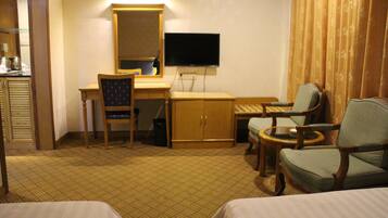 Una camera d'hotel con un letto, due poltrone, una scrivania con una sedia, una televisione e un armadio.