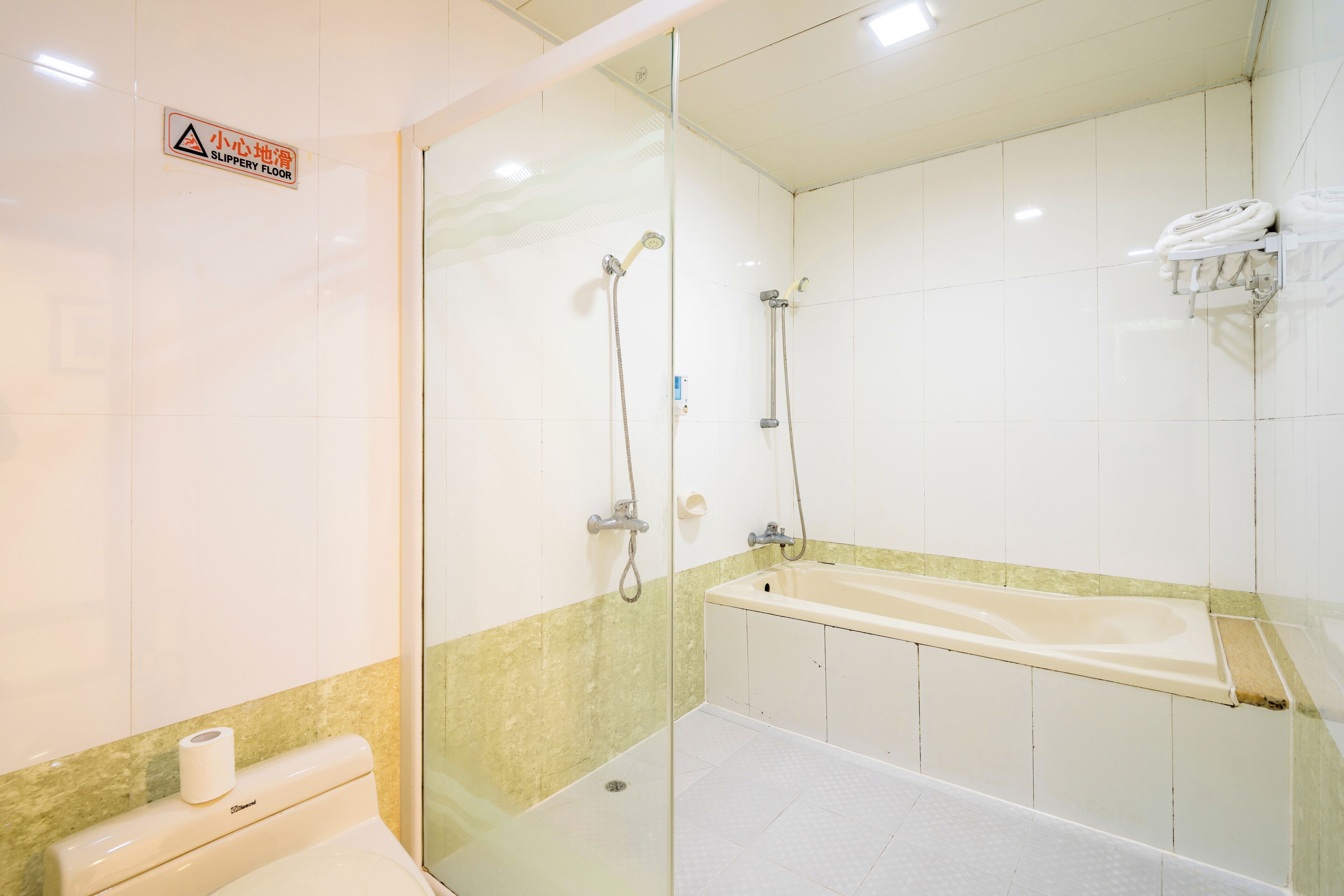 A bathroom with a shower, a bathtub, a toilet, and a towel rack.