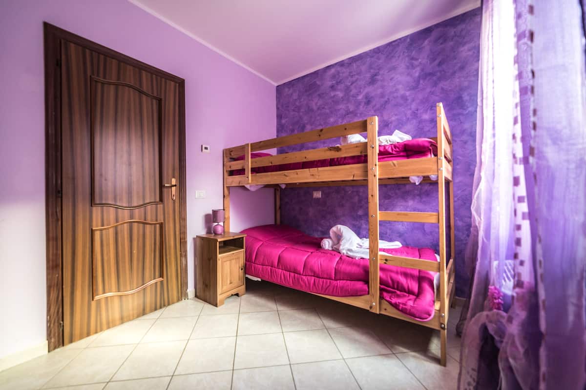 A room with a bunk bed, a wooden wardrobe, and a small bedside table.
