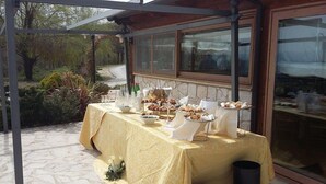 An outdoor buffet table with food and drinks, set up under a covered area with stone walls and windows. - Locanda Belvedere (Rocchetta a Volturno)