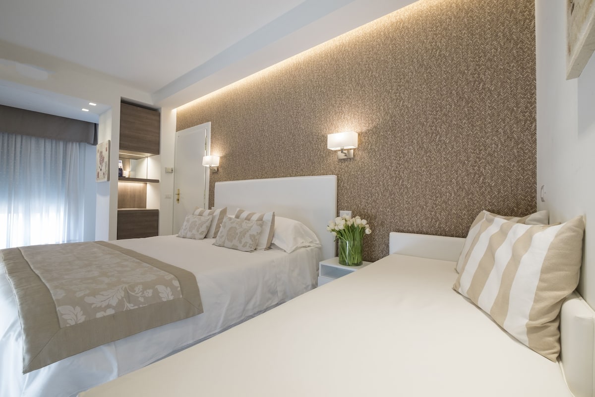 Habitación de hotel con dos camas, un espejo grande y una pared con textura.