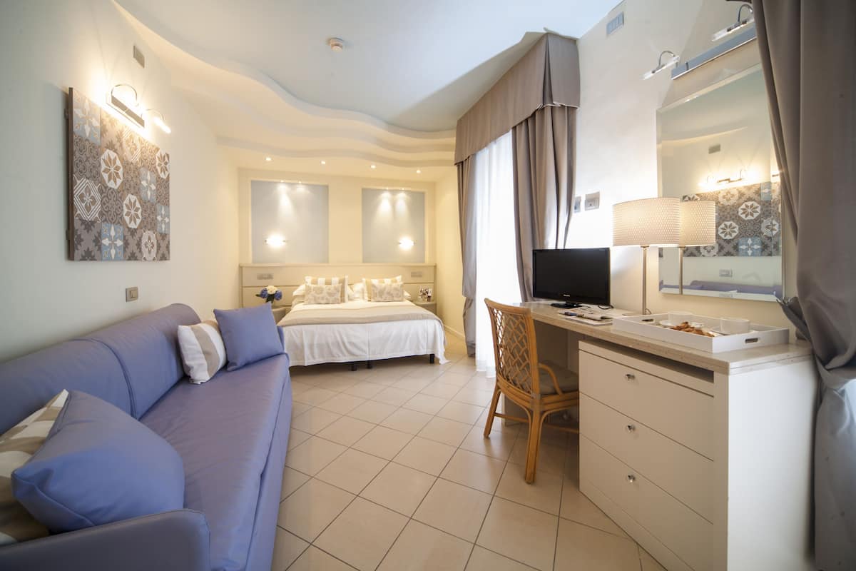 Un dormitorio moderno con una cama, un escritorio, una silla y un televisor.