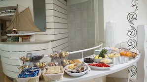 Una mesa de buffet con diferentes tipos de comida y una maqueta decorativa de un velero.