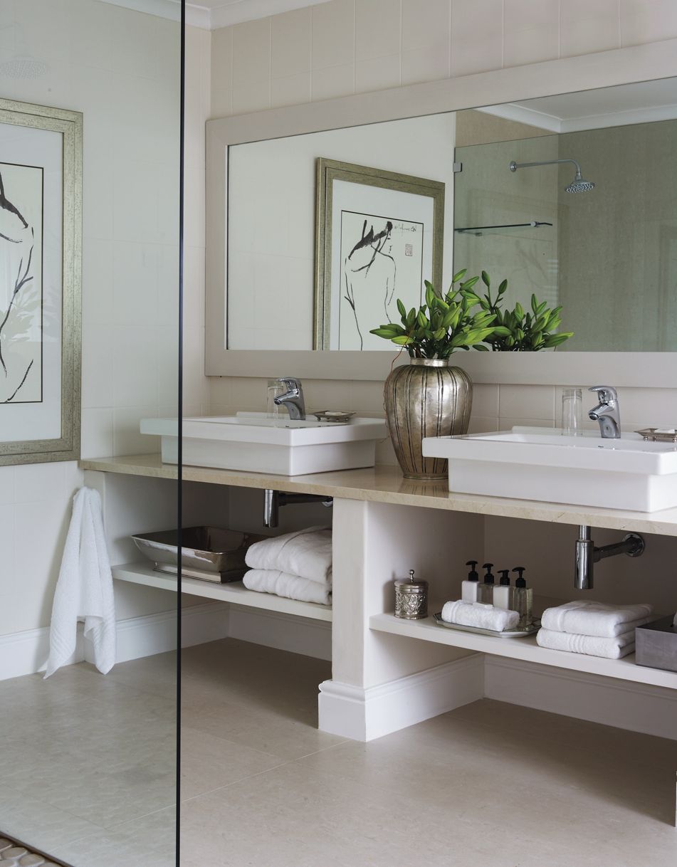 Une salle de bain moderne avec deux lavabos, un grand miroir et une plante en pot.
