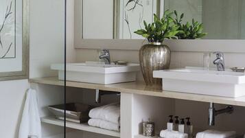 Une salle de bain moderne avec deux lavabos, un grand miroir et une plante en pot.