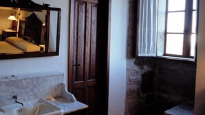 A bathroom with a marble sink, a mirror, and a wooden door.