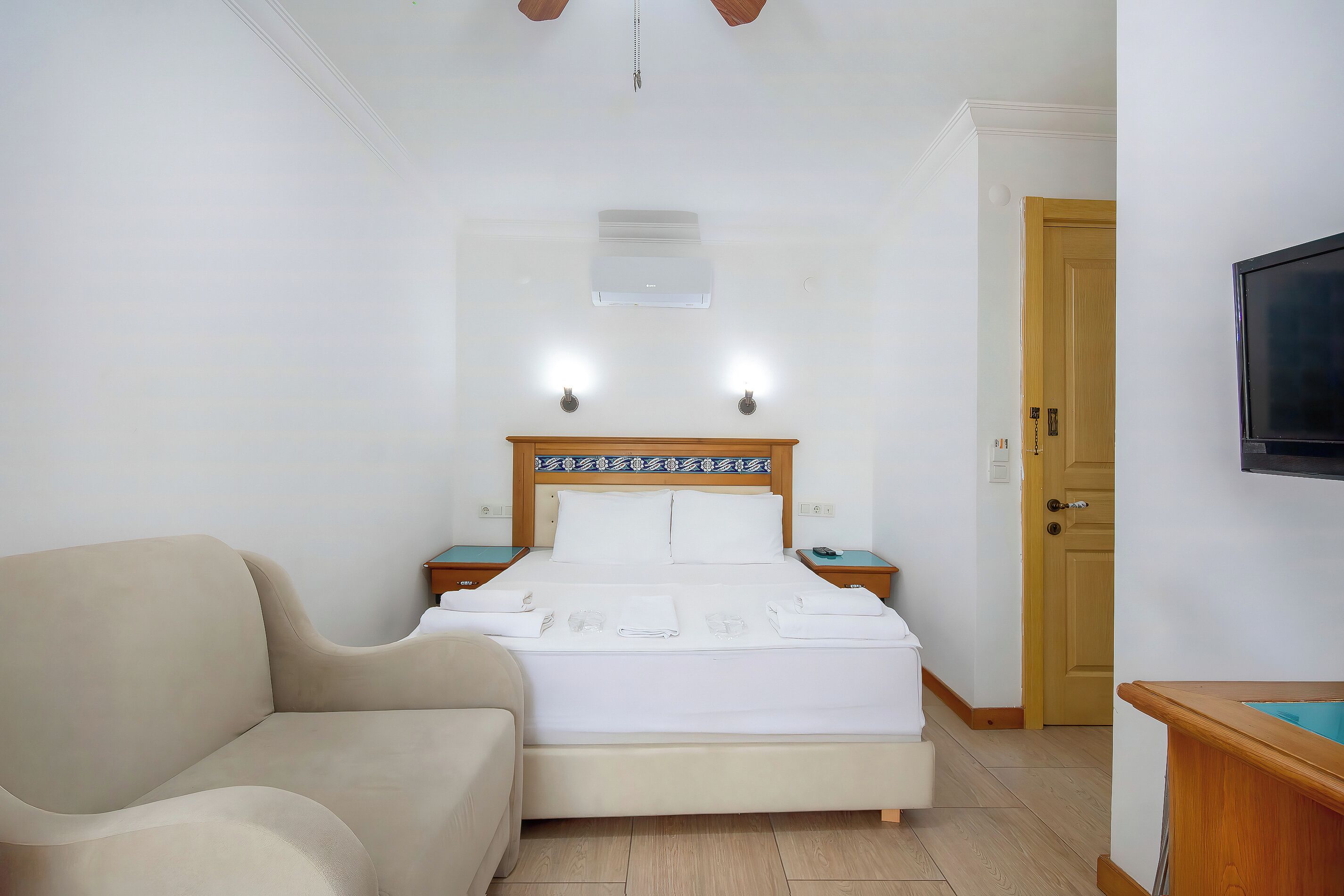 Une chambre d’hôtel avec un lit, un canapé, une télévision et une porte en bois.