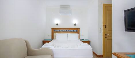 Une chambre d’hôtel avec un lit, un canapé, une télévision et une porte en bois.