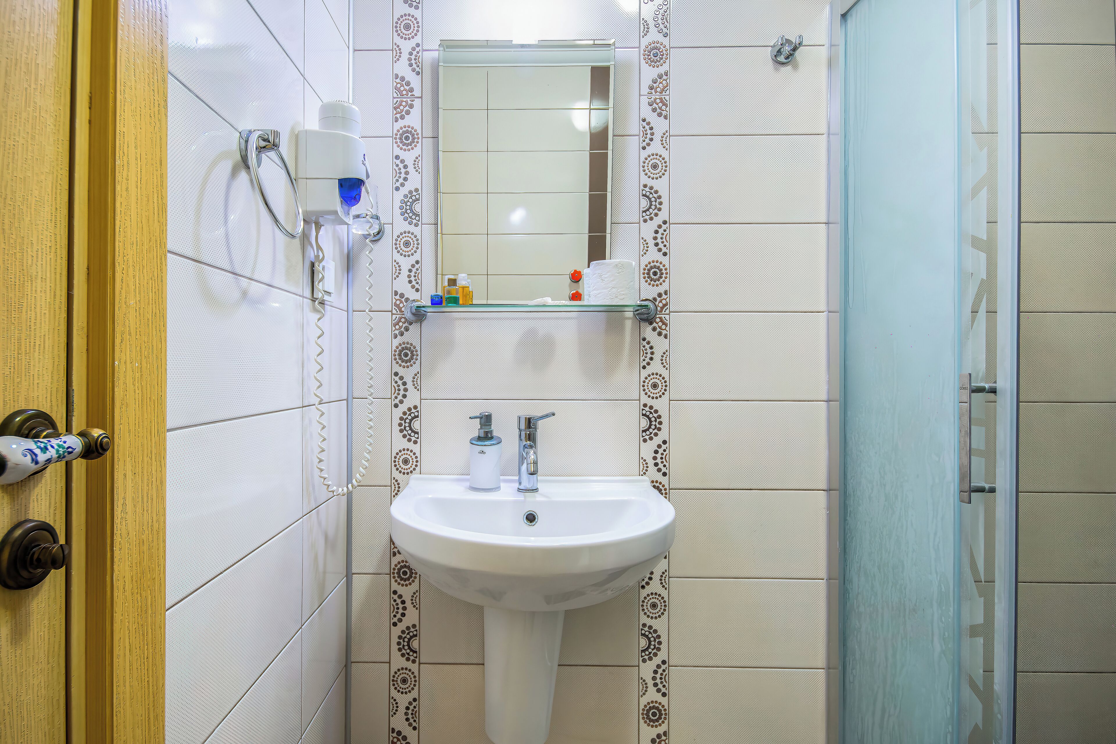 Un baño con un lavabo blanco, un espejo y zona de ducha.