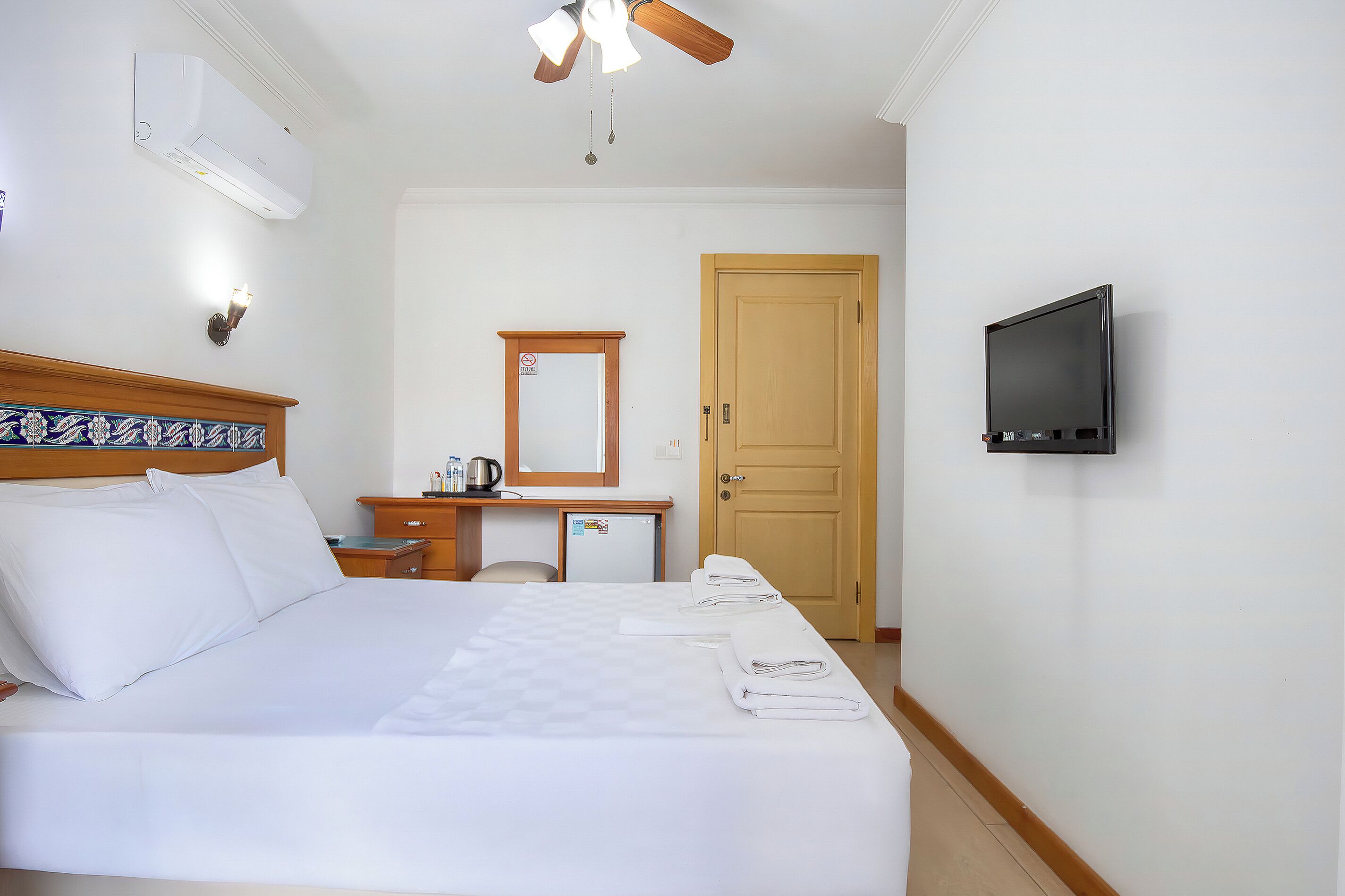 A hotel room with a bed, a desk, a television, and a door.