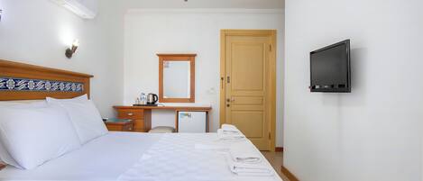 A hotel room with a bed, a desk, a television, and a door.