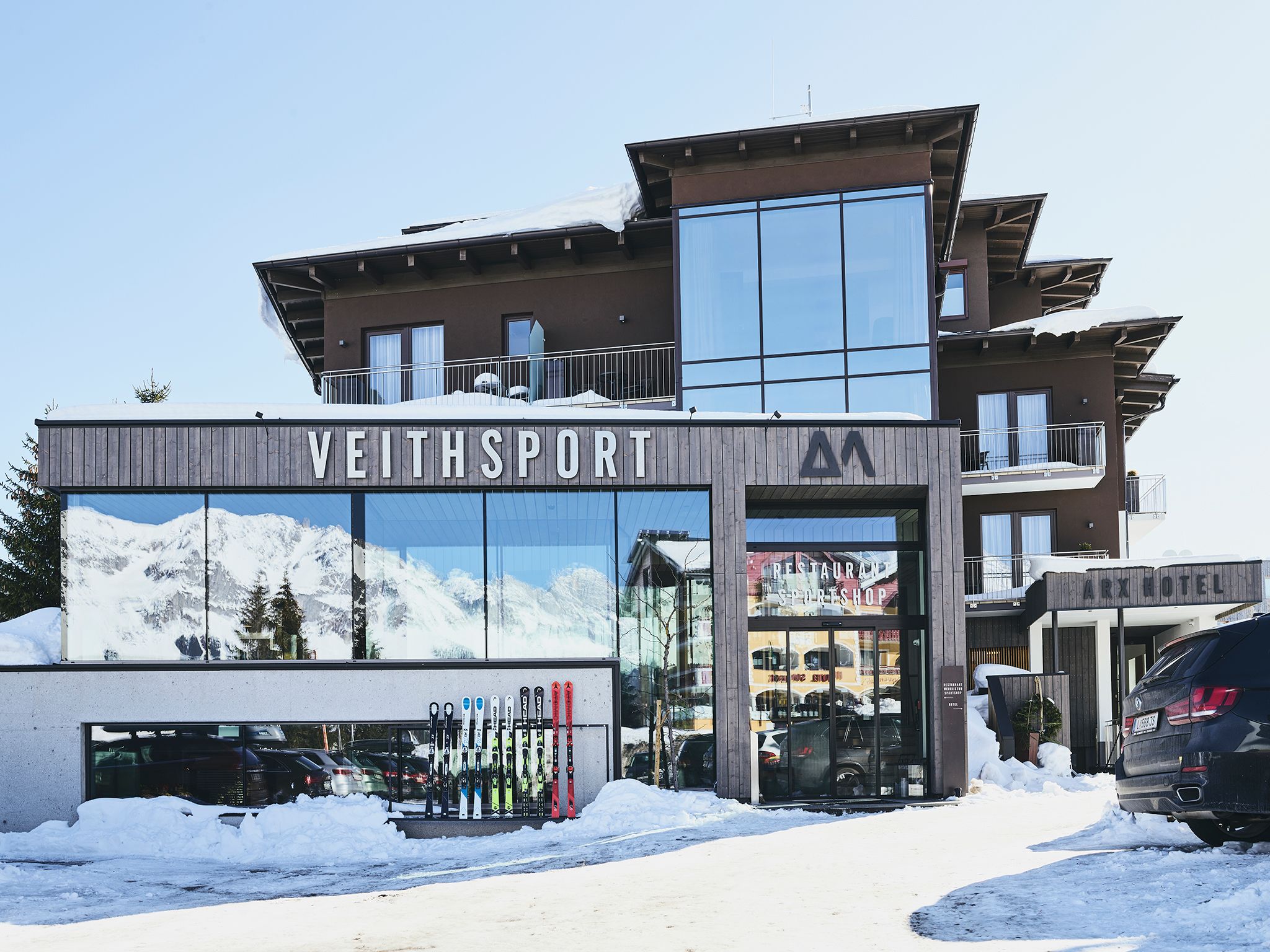 A modern building with a ski shop and restaurant on the ground floor, and a hotel on the upper level.