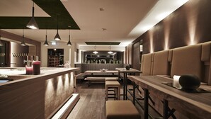 Un interior de restaurante moderno con mesas y bancos de madera, y lámparas colgantes.