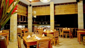 A restaurant with wooden tables and chairs, bamboo blinds, and a hanging light fixture. - Tetirah Boutique Hotel Ubud (Ubud)