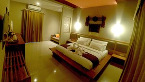 A hotel room with a large bed, bedside tables, a nightstand, an air conditioning unit, and a wall-mounted light fixture. - Tetirah Boutique Hotel Ubud (Ubud)