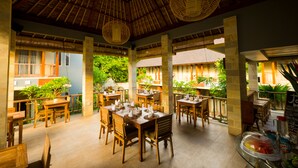 A restaurant with wooden tables and chairs, a tiled floor, and hanging wicker lamps. - Tetirah Boutique Hotel Ubud (Ubud)