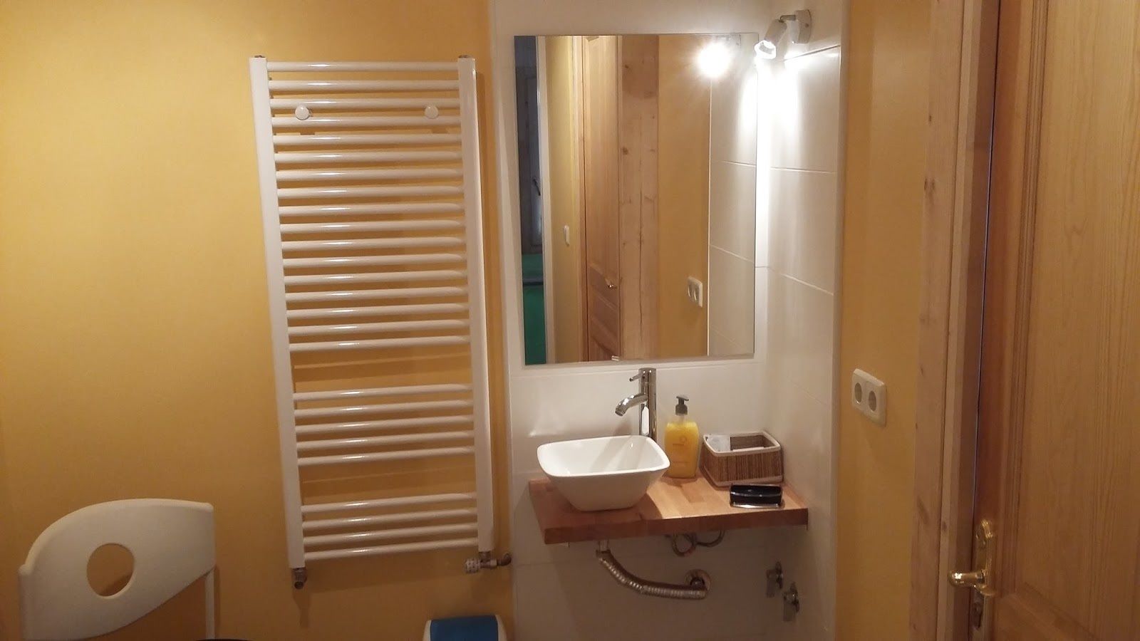 Een badkamer met een witte badkuip, een houten wastafelmeubel met een wastafel, een spiegel en een handdoekhouder.