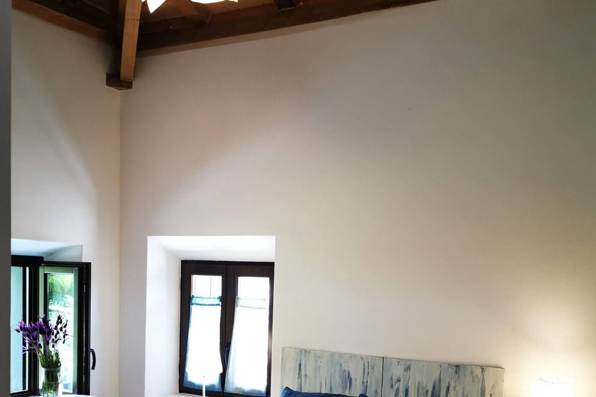 Un dormitorio con cama, una mesita de noche, una ventana y una pequeña mesa con una silla.