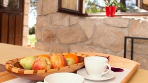 A wooden tray with a bowl of fruit and two white cups on a table.