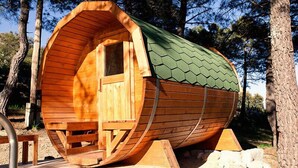 A wooden cabin with a curved roof, a door, and a bench inside.