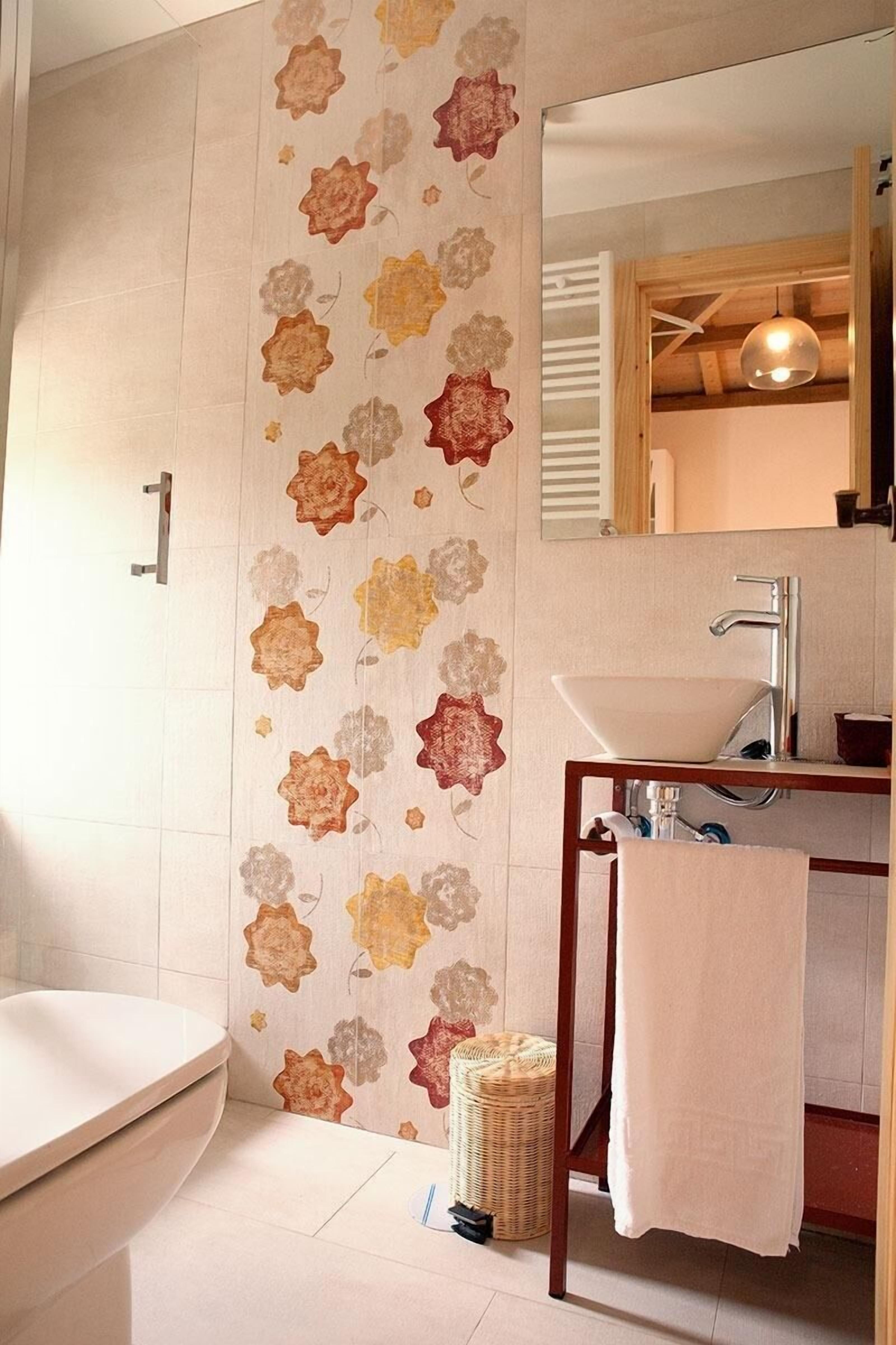 Un baño con una bañera blanca, un tocador de madera con un lavabo, un espejo y un papel tapiz floral.
