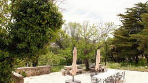 An outdoor patio area with stone benches, a table, and umbrellas.