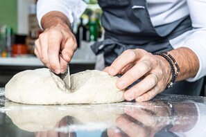 A person kneading dough on a floured surface. - Hotel Gardenazza (Badia)