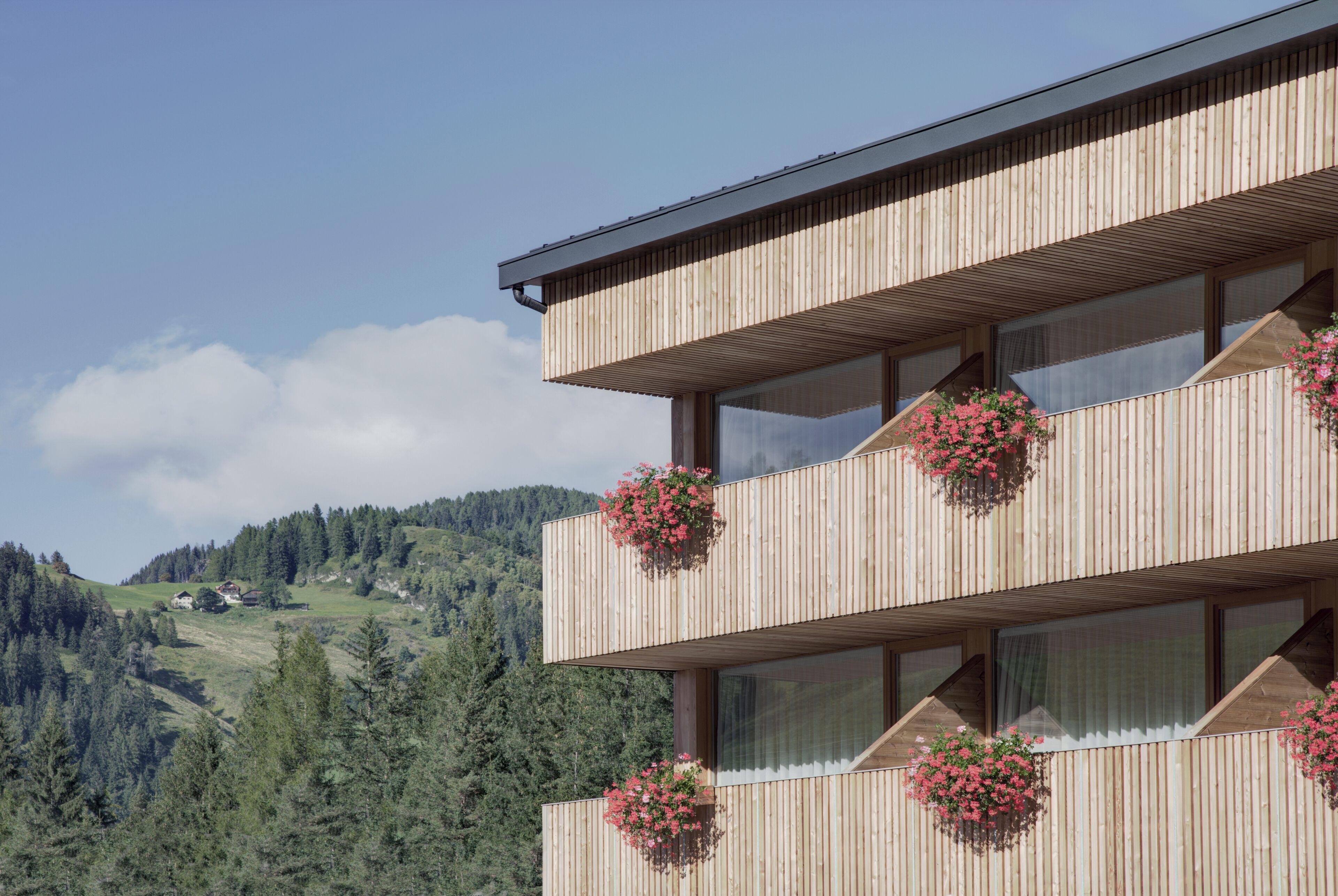 Un edificio in legno a più piani con balconi, ognuno decorato con fioriere pensili.
