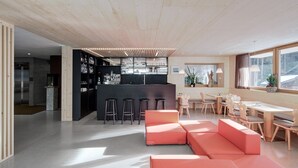 Una cocina moderna con barra, asientos con sofá rojo y zona de comedor con mobiliario de madera.