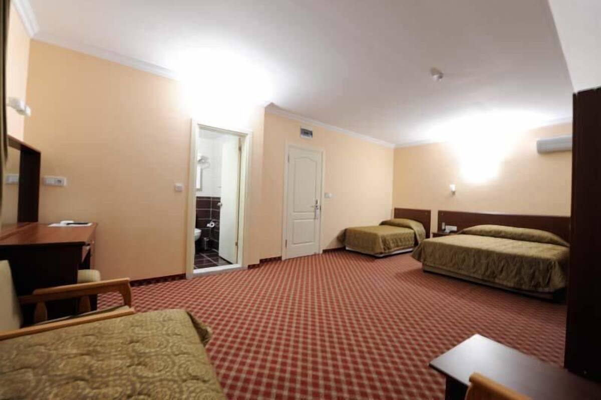 A hotel room with two single beds, a desk, a chair, and a door leading to a bathroom.