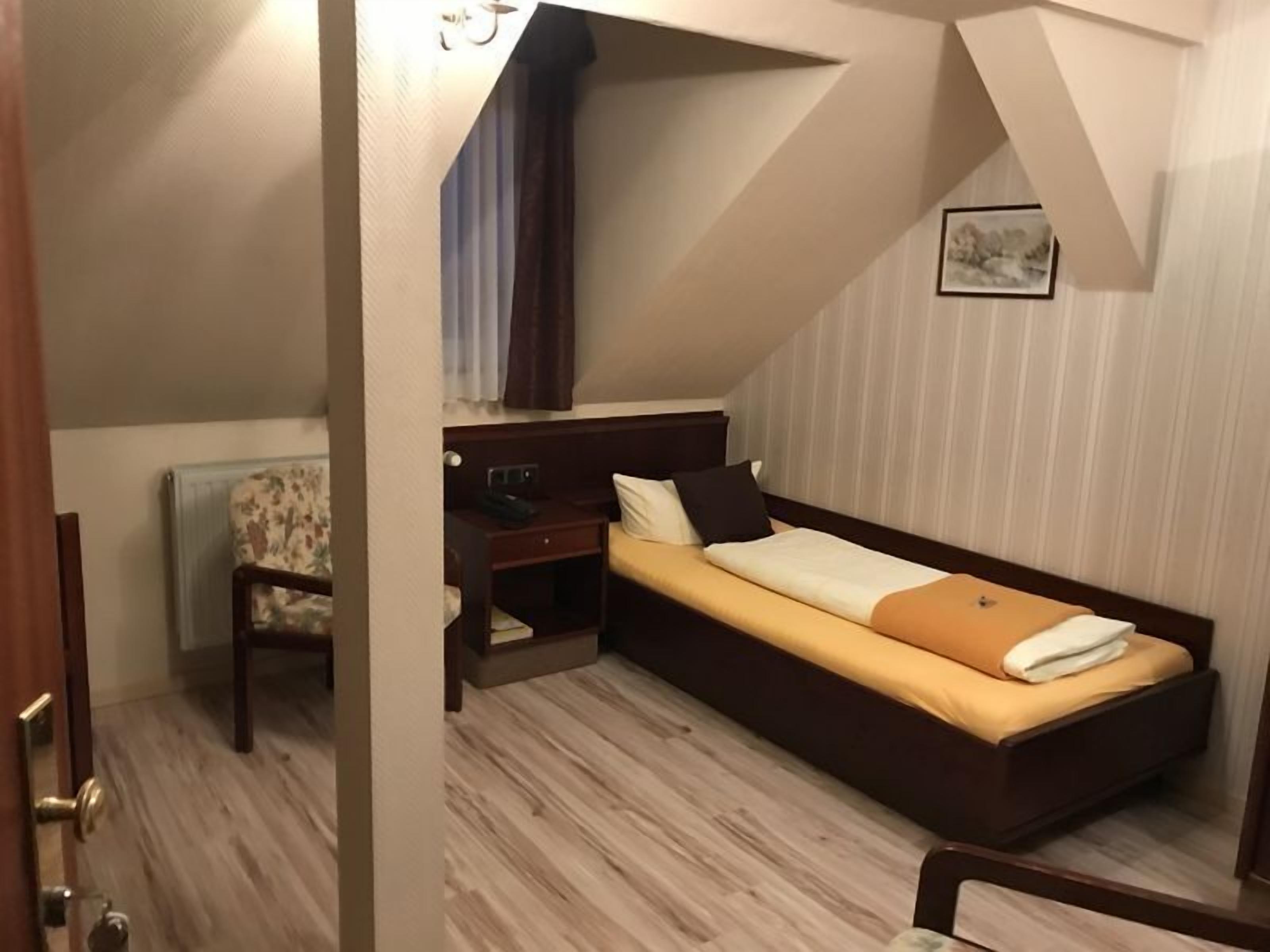 A compact bedroom with a bed, a desk, and a chair.