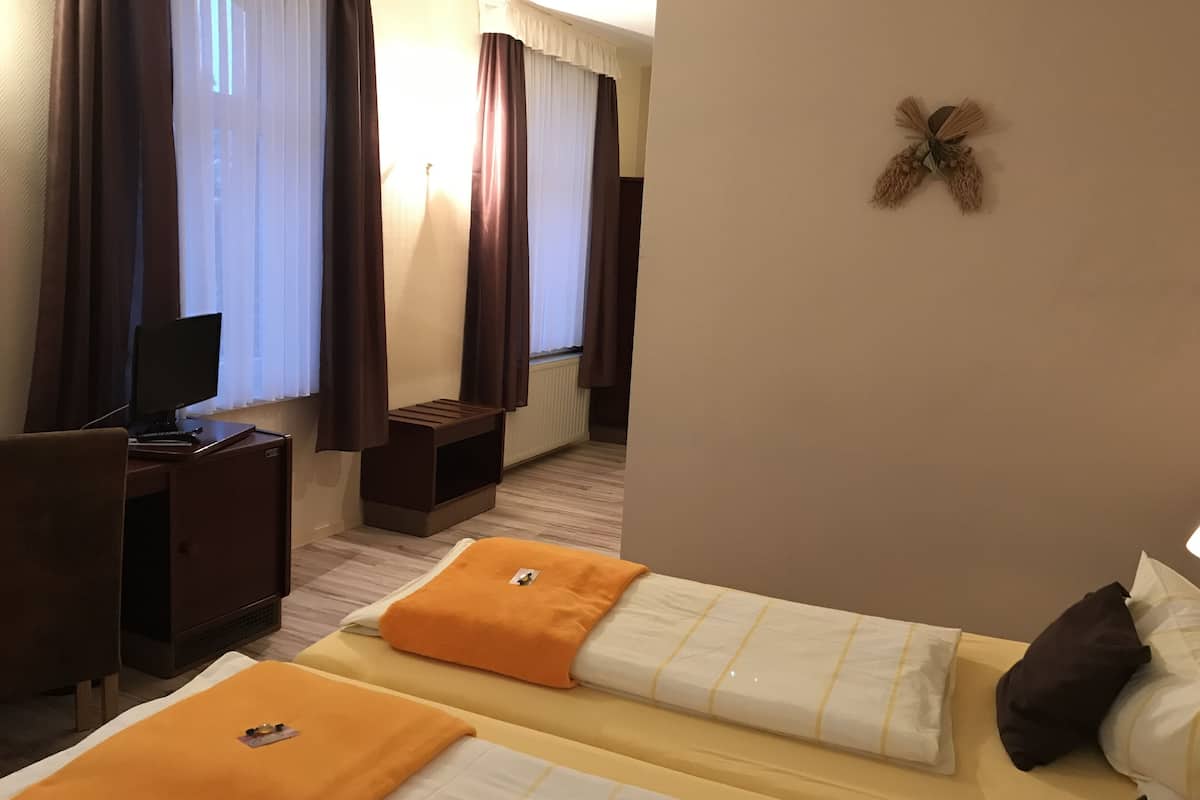 Une chambre d’hôtel avec deux lits, un bureau, un ordinateur et un élément décoratif mural.