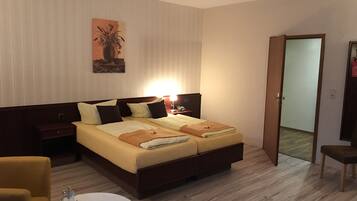 Quarto de hotel com cama, mesas de cabeceira, abajur, cadeira e um quadro na parede.