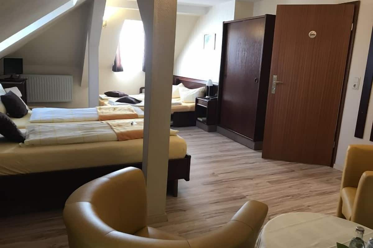 Une chambre d’hôtel avec deux lits, une armoire en bois, une table avec une chaise et une fenêtre avec des rideaux.