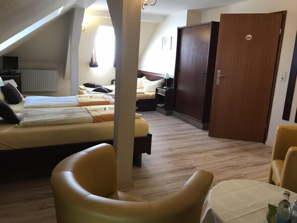 A hotel room with two beds, a wooden wardrobe, a table with a chair, and a window with curtains. - Hotel Schöne Aussicht (Weissenfels)
