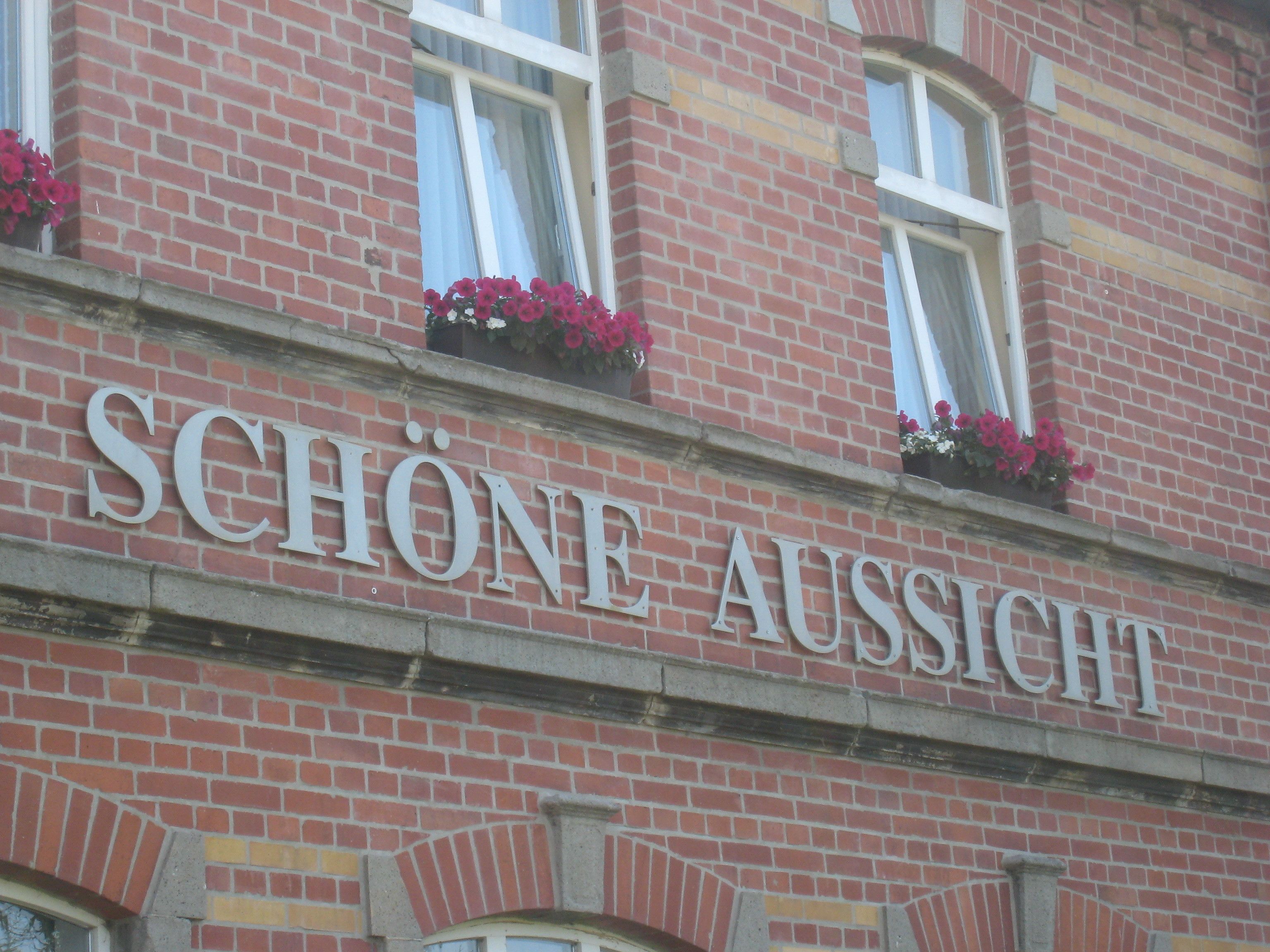 A building facade with the name "SCHÖNE AUSSICTION" in large letters.