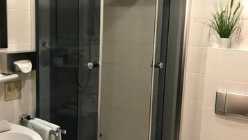 A modern bathroom with a glass-enclosed shower, a white sink, and a toilet.