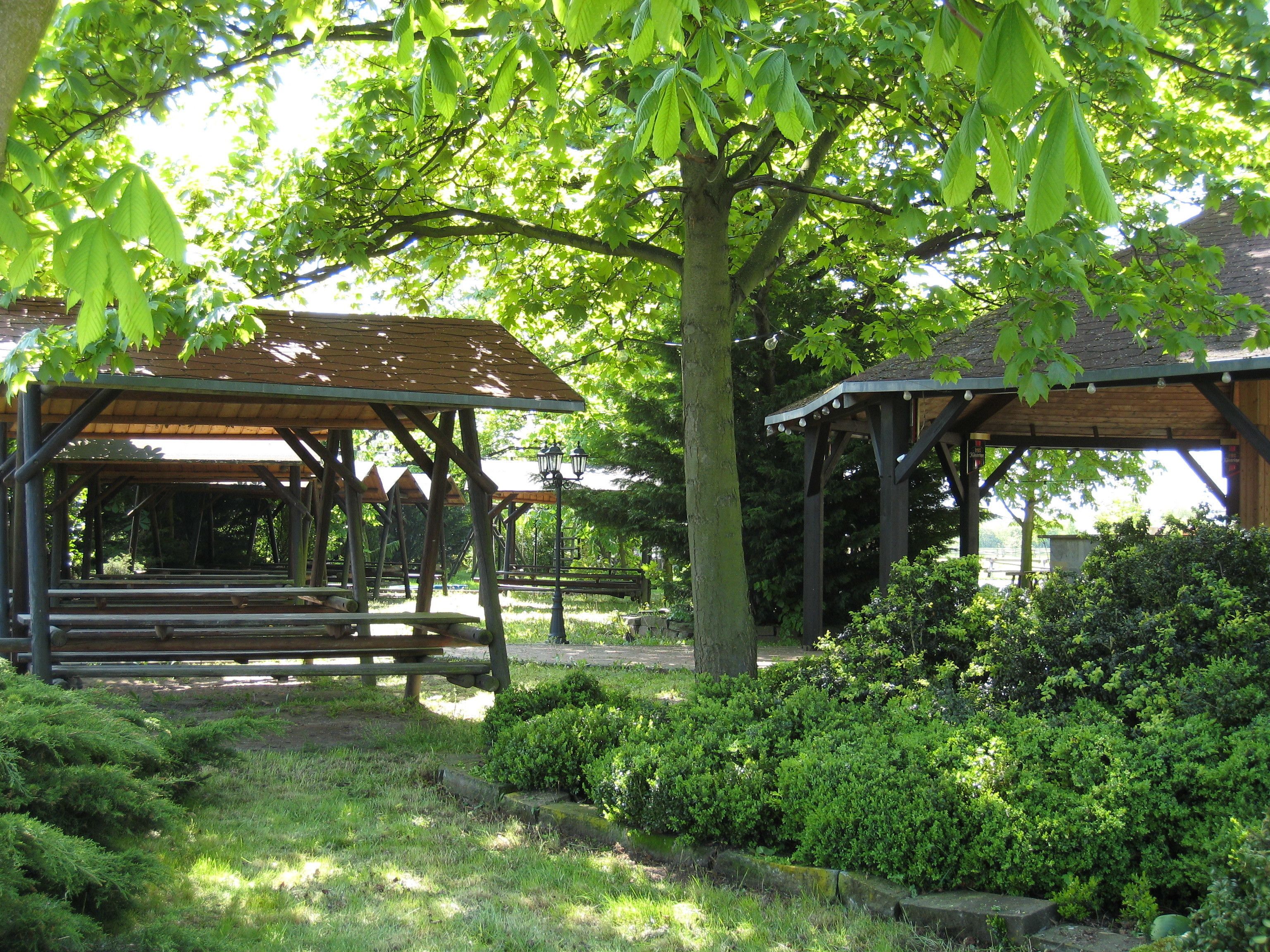 A park with wooden gazebos, benches, and lush greenery.