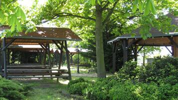 A park with wooden gazebos, benches, and lush greenery.