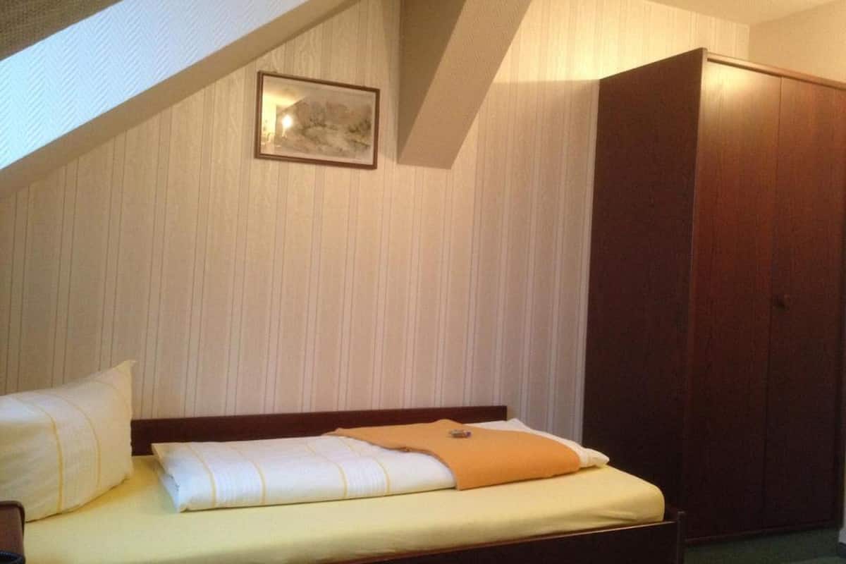 Une chambre à coucher avec un lit, une armoire et un tableau encadré au mur.