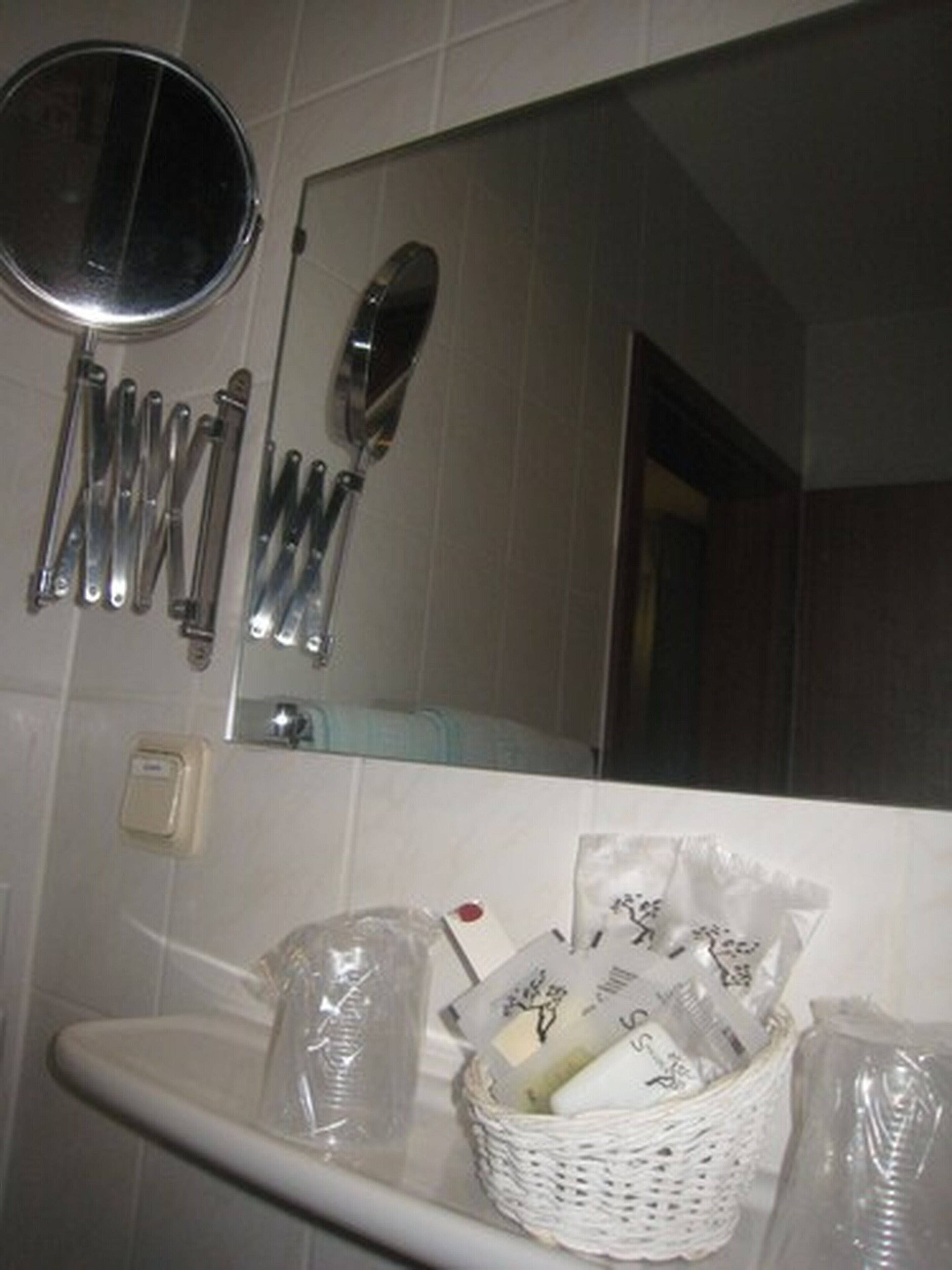 Un baño con lavamanos, espejo y diferentes artículos de aseo.