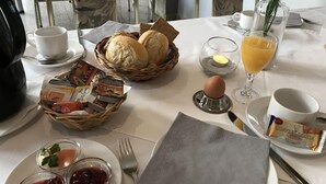 Une table mise pour le petit-déjeuner avec du pain, des œufs, du café et du jus de fruits.