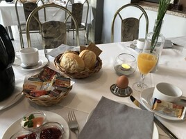 En frukostuppläggning med bröd, ägg, kaffe och juice.
