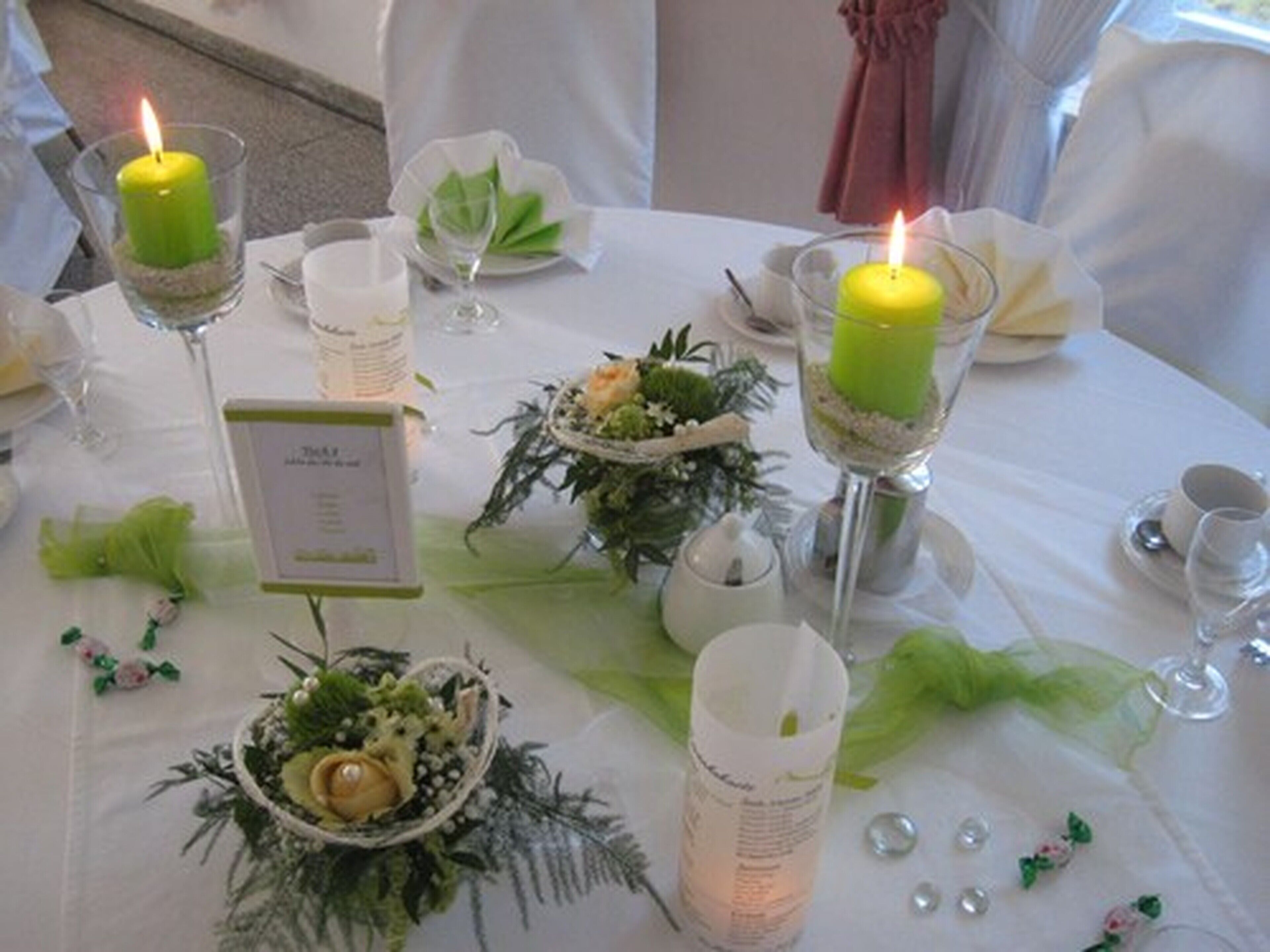 Una mesa dispuesta con velas, copas y centros de mesa florales.