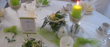 Una mesa dispuesta con velas, copas y centros de mesa florales.