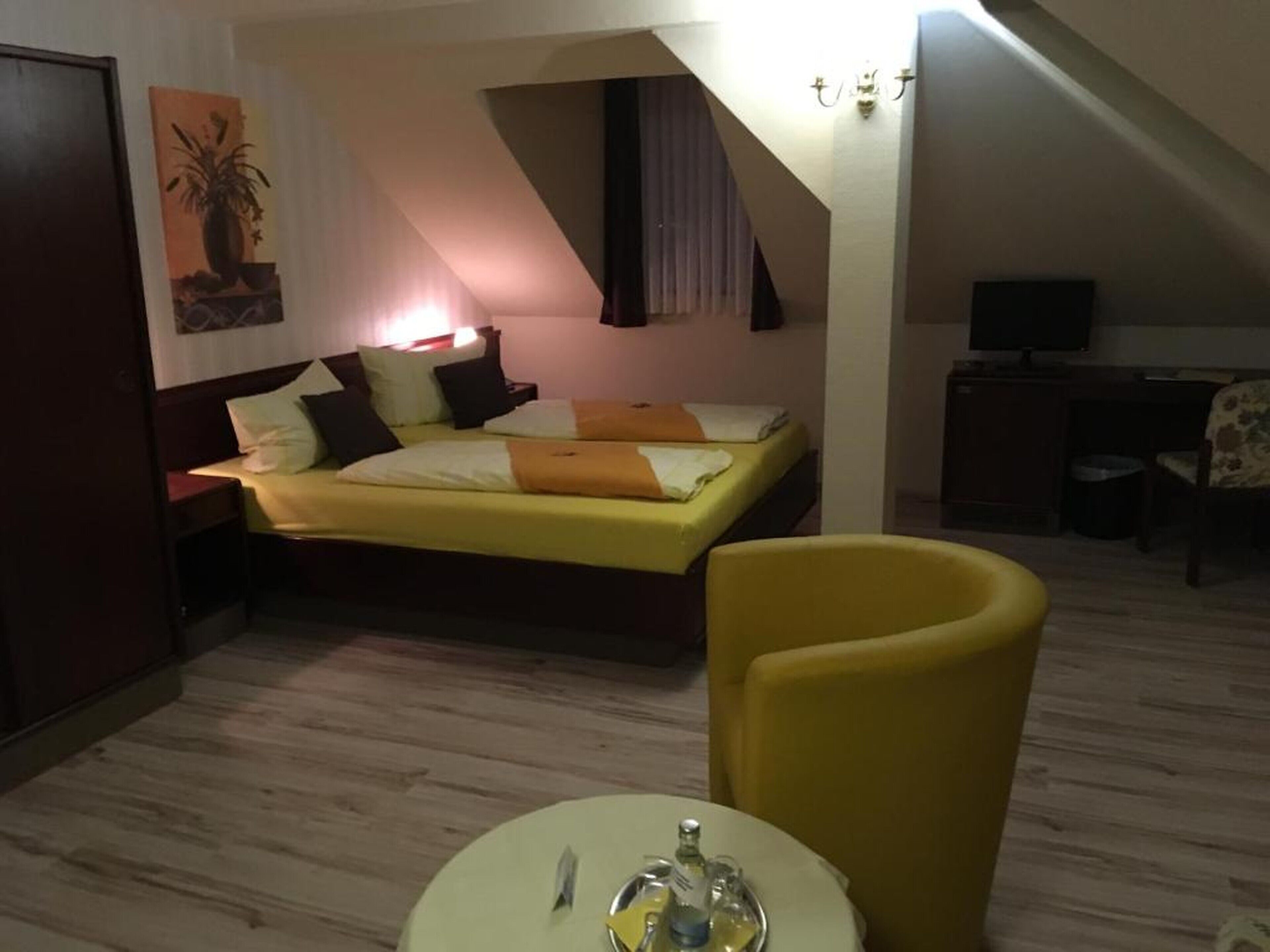 A bedroom with a bed, a chair, a desk, and a television.