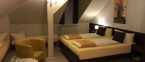 A hotel room with a large bed, two bedside tables, a chair, and a small table with a lamp.